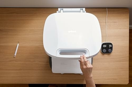 Hand using a modern air fryer on a wooden counter.